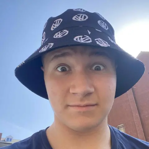 How to get one when you have zero work experience Oliver Holton A selfie of a man in a black and white patterned bucket hat. He is stood outside and in the background there is a building and the sky