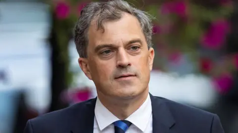 Julian Smith says David Cameron was 'cavalier' in handling of Brexit Getty Images Julian Smith is outside. Flowers are behind him. He's wearing a navy suit.