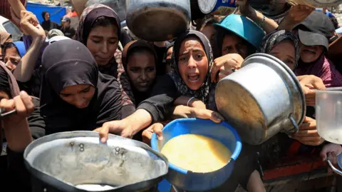 Almost a third of people in Gaza 'not eating for days,' UN warns Reuters A crowd of Palestinians push up against each other with their arms outstretched holding pots and buckets, hoping for food