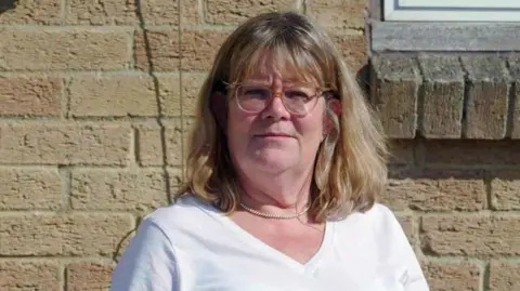 Dubious sales tactics at two leading estate agencies uncovered by BBC investigation BBC Headshot of Julie, standing outside in front of a pale brick wall. She has straight shoulder-length blonde hair with a fringe and has clear-framed glasses. She is wearing a white v-neck t-shirt and a pearl necklace.
