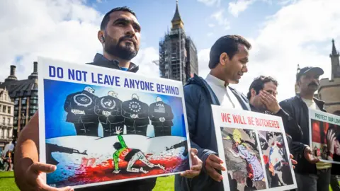 UK offered to speed up resettlement case of Afghan who posted leaked data online Getty Images Protesters in London hold placards calling for the safe evacuation of Afghans that had worked with the British military. The posters read: "Do not leave anyone behind". The image shows a man wearing a t-shirt with an Afghan flag on his knees in a pool of blood, grasping for help from four men who are looking the other way.
