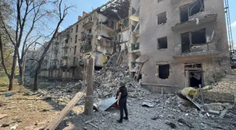 Moscow airports temporarily closed after Ukraine drone attacks Donetsk Regional State Administration A person in a helmet stands looking at a damaged building