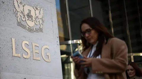Urgent action needed to halt exodus of firms leaving UK, says CBI Getty Images A woman wearing a brown coat walks by the London Stock Exchange in London, she's on her phone and is wearing glasses