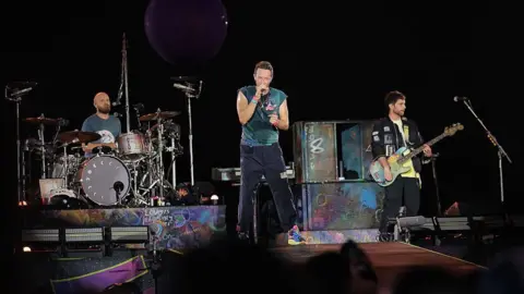 Astronomer's 'clever' PR move embracing CEO scandal Getty Images Three members of Coldplay on stage in the US. Chris Martin is in the middle with drummer Will Champion to his right and bassist Guy Berryman to his left.