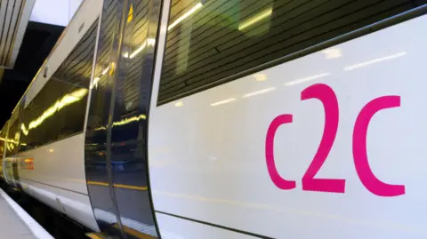 c2c trains are nationalised and return to public ownership c2c A white train with c2c printed on the side in pink. The train is parked next to a platform.