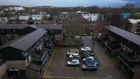 London heat network users say price cap lack has cost them dearly An aerial view of the Consort Estate in London. There is a car park below and terraced housing at either side of it.