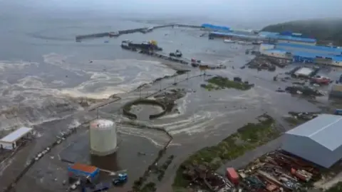 Tsunami alerts scaled back after huge earthquake prompts evacuations across Pacific Geophysical Survey Of The Russian Academy Of Sciences via EPA Aerial shot showing brown ocean water flooding into industrial land