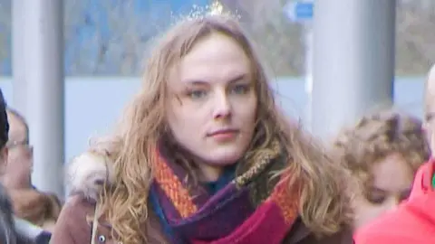 Trans changing room row nurse cleared of misconduct as tribunal resumes Dr Beth Upton has long brown hair and wears a colourful scarf and a brown parka jacket.