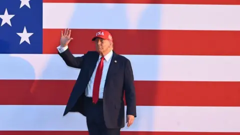 US debt is now $37trn – should we be worried? Getty Images Donald Trump waves wearing a baseball cap and suit in front of a huge US flag poster