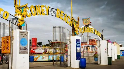 Porthcawl Coney Beach fair to close in October after 100 years Getty Images Entrance gates to amusement park with Coney Beach Pleasure Park in yellow letters on top of the gates and attractions visible behind