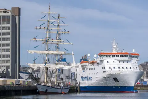 'Party city' event gets under sail PA Media Tall ship in Aberdeen, with a white NorthLink ferry alongside, in Aberdeen harbour.