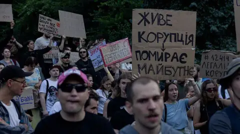 Ukraine backlash grows after Zelensky strips anti-corruption bodies of independence Getty Images Ukrainians stand in opposition in Kyiv to a new law - holding up placards