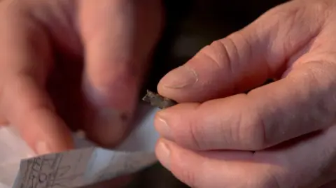 They took shrapnel out of my heart Kevin McGregor / BBC Ukrainian serviceman Serhiy Melnyk holds above a scrap of paper a small grey piece of shrapnel once lodged in his heart.