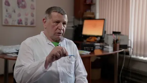 They took shrapnel out of my heart Kevin McGregor / BBC Serhiy Maksymenko sits in his consulation room. He wears a white doctors coat. He was part of the team of surgeons who removed the shrapnel from Serhiy’s heart.