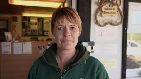 Imported dogs 'posing risk to UK', RSPCA warns A woman with auburn hair tied back with a fringe looks directly into the camera, she is wearing a green fleeced top over a dark green hoodie. Behind her is the blurred out background of the dog rescue where she works.