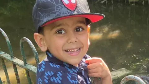 NHS failed to hear concerns of family in death of five-year-old boy Handout Yusuf Nazir, a small boy, stands next to some railings by a stream. He smiles for the camera and wears a blue short sleeved short and a baseball cap with the Spiderman logo on it.
