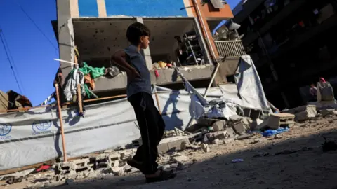 Israel to send team to Gaza talks despite Hamas demands, PM says Reuters A Palestinian boy walks near a UNRWA school sheltering displaced people that was hit in an Israeli strike, in Gaza City (5 July 2025)