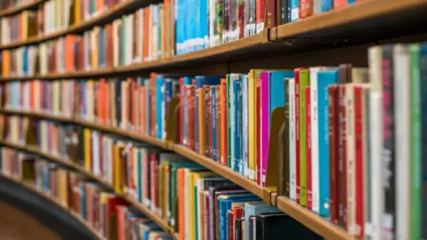 Trans books removed from children's library, Reform council says Getty Images Rows of books on shelves. The books are all different colours.