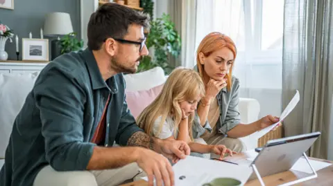 Millions of homeowners to see mortgage payments rise Getty Images A couple sit with a girl on a sofa looking at a laptop and a piece of paper