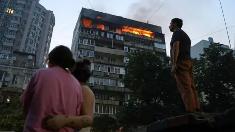 Ukraine to receive US Patriot air defence systems, says Trump Getty Images People look at burning apartments in a high-rise residential building hit by Russian shelling on July 10, 2025 in Kyiv, Ukraine.