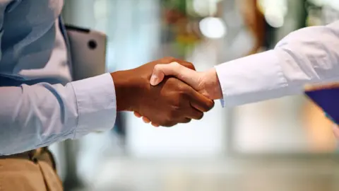 How are trade deals actually negotiated? Getty Images A man and a woman shake hands on a deal
