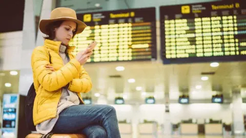What are my rights if my flight is cancelled or delayed? Getty Images A lady in a hat and yellow jacket sat in front of airport departure boards, sat on her suitcase and looking in to her mobile phone.