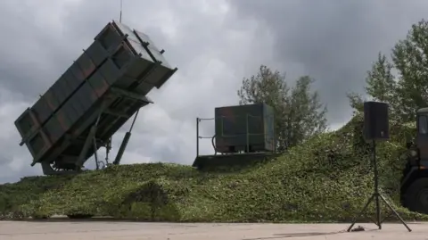 Ukraine to receive US Patriot air defence systems, says Trump Getty Images A Patriot system received by Ukraine is seen on the Day of Ukrainian Air Force on August 4, 2024 in Ukraine. The camouflage-painted rectangular system is raised at an angle on a platform on top of a grassy mound.
