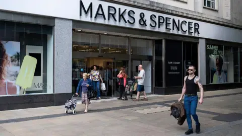 M&S 'fully back online in four weeks', says boss Getty Images Marks and Spencer store in Swansea with people walking in and out of the store and a man walking in front of it