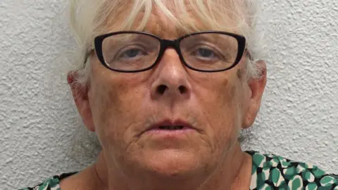 'Gangsta Debbs' - the granny who used her family to run a drug gang Metropolitan Police Deborah Mason, a woman with shortish grey hair who is standing against a white wall and wearing a green, black and white speckled top as well as dark-rimmed glasses.