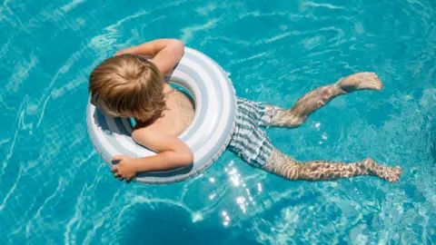 Free summer swimming lessons for 6,000 Wiltshire children Getty Images A child swimming in crystal blue water, he is in the middle of an inflatable ring.