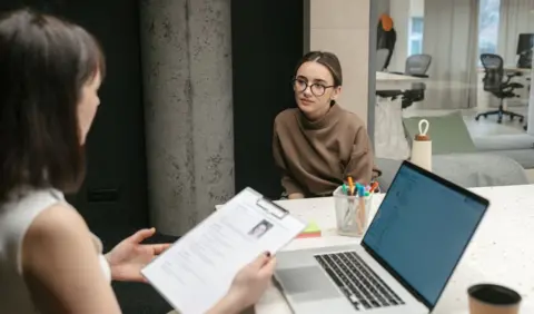 How to get one when you have zero work experience Getty Images Woman holds CV of a young woman sat in front of her in an office setting