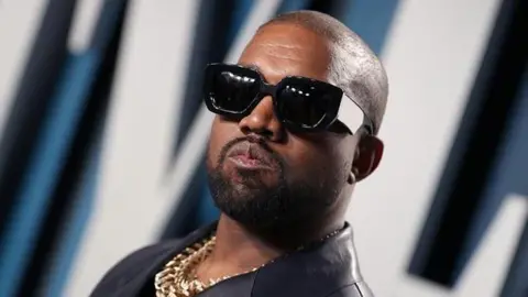 Kanye West's ex-assistant in hiding after filing sexual assault claims, lawyer says Getty Images Kanye West with sunglasses on posing for a picture. He is also wearing a gold chain.
