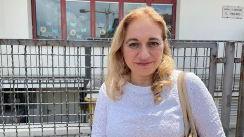 'The village will die' - Italy looks for answers to decline in number of babies Headteacher Luana Scarfi, a woman in a white top with blonde hair