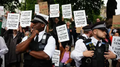 More than 20 arrested at protest, Metropolitan Police say PA Media Police standing in front of protesters holding placards in support of Palestine Action