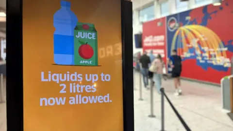 Edinburgh Airport liquid limit increased from 100ml to two litres BBC An orange airport video signboard saying "Liquids of up to 2 litres now allowed" with passengers carrying hand luggage walking in background