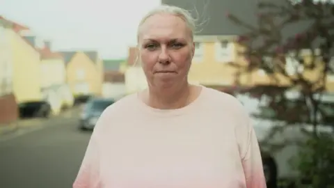 Imported dogs 'posing risk to UK', RSPCA warns A woman with tied back blonde hair looks at the camera. She is not smiling. She is wearing a pale pink jumper and is standing in a residential street, which is blurred