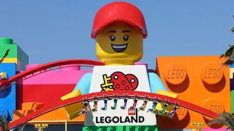 China bets on Western theme parks to lift spending Getty Images A photo of a towering Lego minifigure mascot standing between two red rollercoaster tracks in Legoland Shanghai.