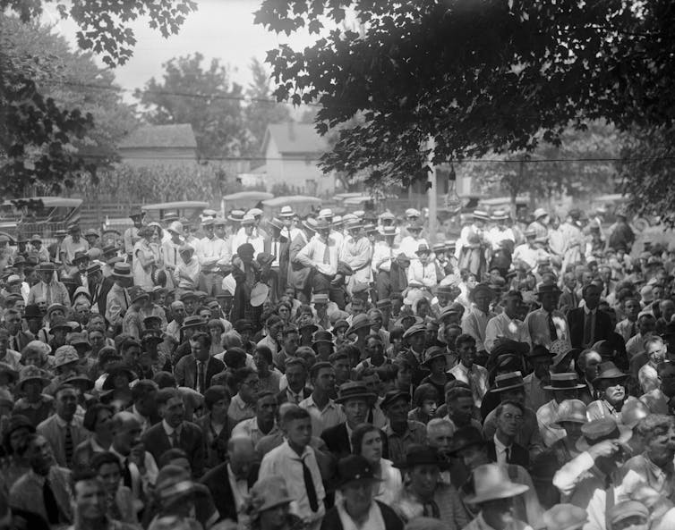 1 in 4 Americans reject evolution, a century after the Scopes monkey trial spotlighted the clash between science and religion A large group of men and women standing outside, intently looking ahead.