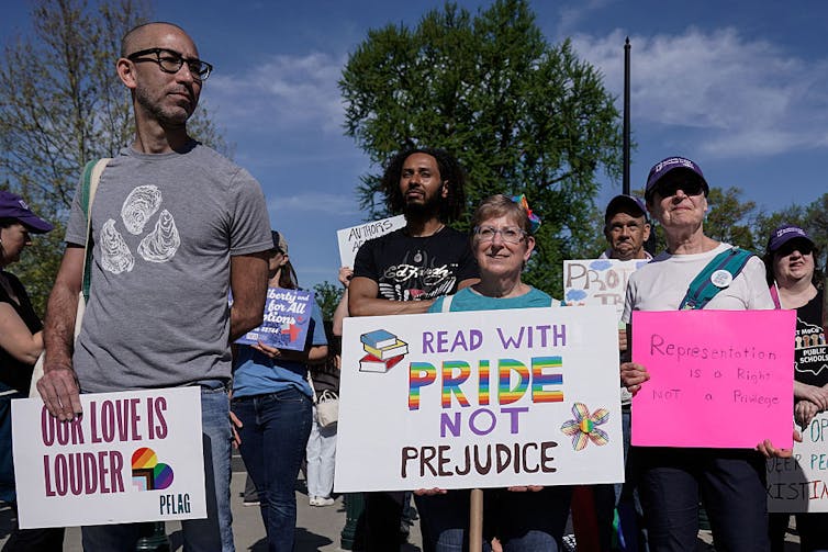 In LGBTQ+ storybook case, Supreme Court handed a win to parental rights, raising tough questions for educators A handful of people stand outside holding placards with messages including 'Read with pride not prejudice.'