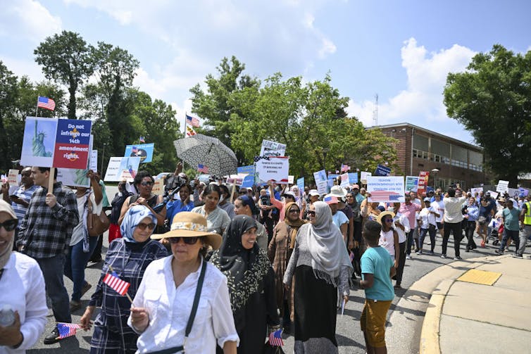 In LGBTQ+ storybook case, Supreme Court handed a win to parental rights, raising tough questions for educators A protest outside, with people walking down a street as they carry placards.