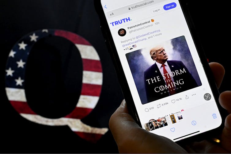 How the QAnon movement entered mainstream politics – and why the silence on Epstein files matters A mobile device with an image of Donald Trump alongside a QAnon sticker using an American flag.