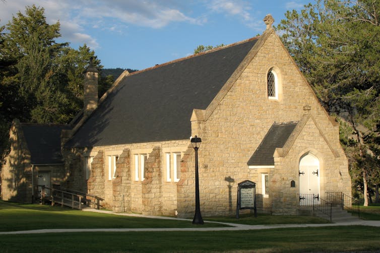 A small stone church features a pitched roof, arched windows and a prominent entrance.