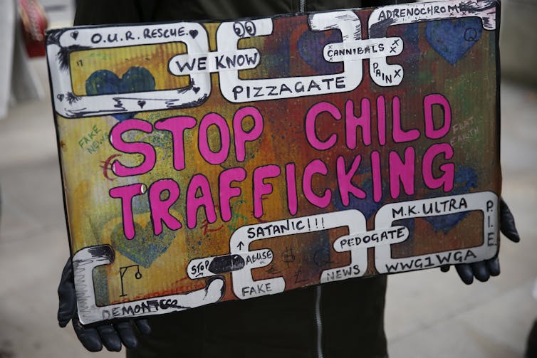 How the QAnon movement entered mainstream politics – and why the silence on Epstein files matters A poster with the slogan 'Stop Child Trafficking' in big letters, with smaller ones saying 'pizzagate' and other phrases.