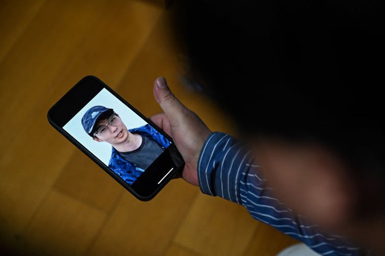 It is becoming easier to create AI avatars of the deceased − here's why Buddhism would caution against it A person holding a phone with the face of a young man wearing a baseball cap on its screen.