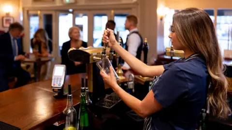 Half of UK job losses in hospitality, say bosses Getty Images A female member of bar staff pulling a pint in a half-crowded bar