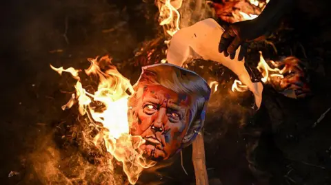 PM Modi says make and spend in India as 50% tariffs kick in AFP via Getty Images A burnt effigy of US President Donald Trump seen with flaming embers. Activists from different unions were part of a protest against the tariff hikes imposed by the US on India during a demonstration in Kolkata on August 13, 2025.