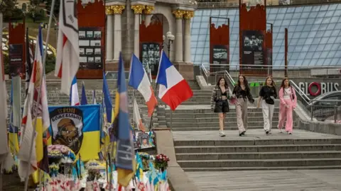 Zelensky vows to continue fighting as Ukraine marks independence day Reuters People pass by a makeshift memorial to fallen Ukrainian defenders in Kyiv's Independence Square. Along with flowers and the Ukrainian flag there are also flags of other countries, including France.