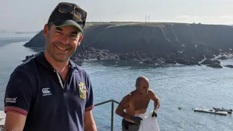 Pembrokeshire's Thorne Island fortress turned into £3m party space Mike Conner Mike Conner stands to the left of the photograph in front of the sea, he is wearing a blue polo shirt and dark cap and has short stubble. Behind him a man with no shirt on is walking up some steps carrying a bag. A small island can be seen in the background.