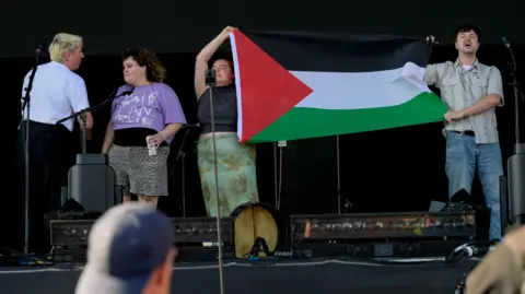 Bands boycott Victorious music festival after group 'cut-off' Getty Images Four members of The Mary Wallopers stood on the Victorious Festival stage holding a Palestinian flag and with mouths open appearing to chant