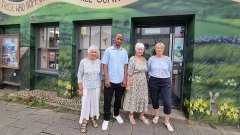 Somerset food banks say demand is rising as donations drop Alex Mayfield The team of volunteers at The Lord's Larder in Chard stand outside the food bank, the food bank is painted to look like a landscape in the spring